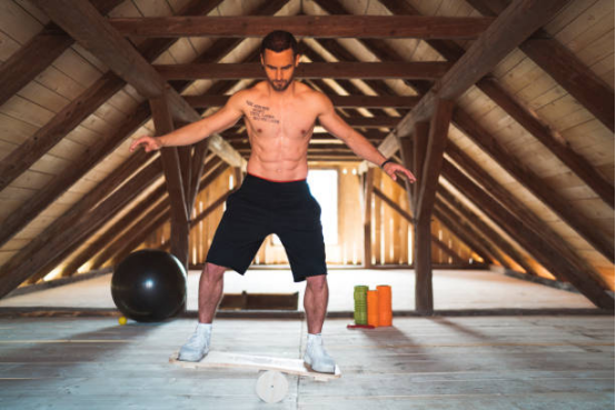 A person performing a rapid forward and backward jump on a balance board for fat-burning.