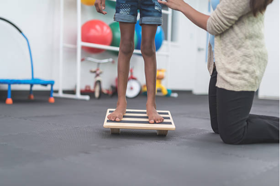 A patient using a balance board for ankle rehabilitation exercises