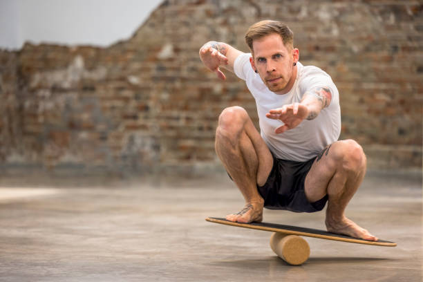Man squatting on a wooden balance board, focusing on core strength and balance training.
