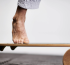 Close-up of foot on a wooden balance board with cork roller.