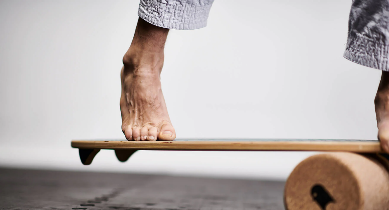 Close-up of foot on a wooden balance board with cork roller.