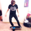 Young man in black shirt practices balance on a blue and black balance board.