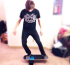 Young man in black shirt practices balance on a blue and black balance board.