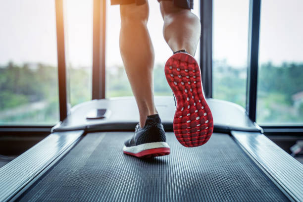 Close-up of runner's feet on treadmill for fitness, aiding balance board training.