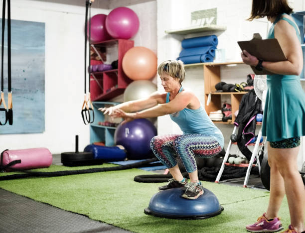 Woman squats on a BOSU ball, enhancing balance similar to a balance board workout.