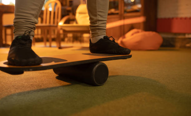 Close-up of feet in trainers on a balance board, improving core strength indoors.