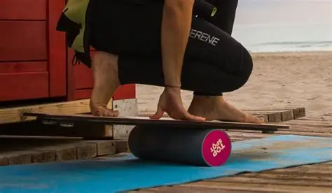 Surfer training on a balance board on a wooden deck by the beach.