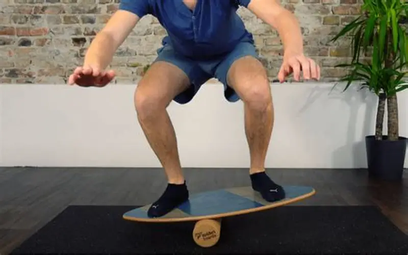 Man performs squats on a patterned balance board with roller, improving stability.