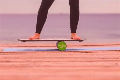 Bare feet balancing on a balance board on a dock over water, practicing outdoors.