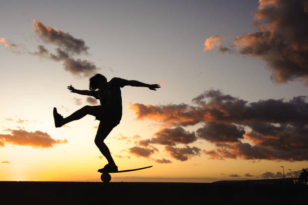 Silhouette of person balancing on a balance board against a beautiful sunset sky.
